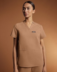 healthcare working standing up wearing khaki colored scrubs