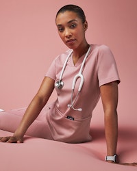 Woman in pink scrubs lounging with pink background
