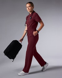 Women in scrubs walking while holding a backpack