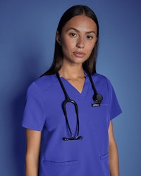 healthcare working wearing galaxy blue scrub top standing against blue background